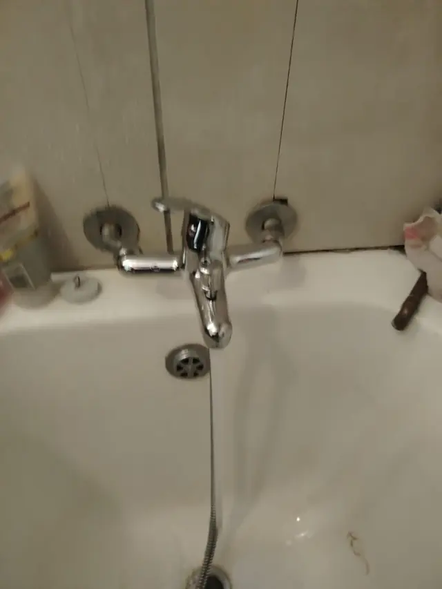 Chrome bath mixer tap with water running into a white bath