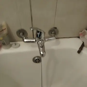 Chrome bath mixer tap with water running into a white bath