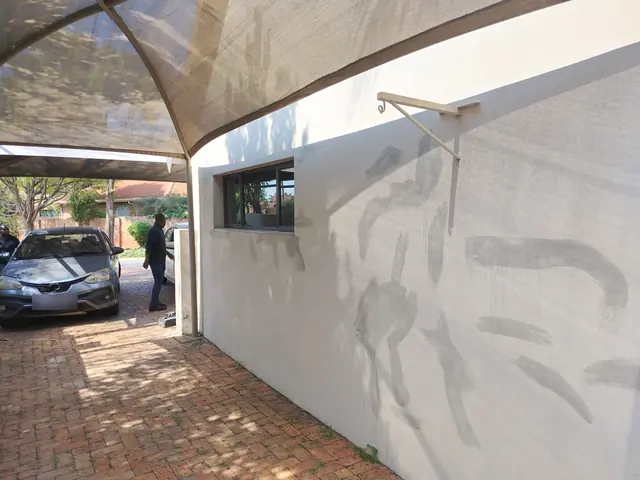 Carport wall with brushed grey primer and filler marks beside a window