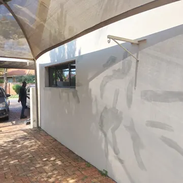 Carport wall with brushed grey primer and filler marks beside a window