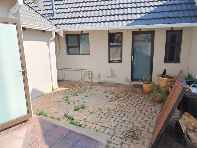 Paved courtyard with cream walls showing grey patches of filler and a drain