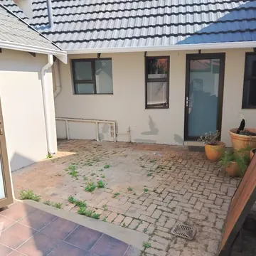 Paved courtyard with cream walls showing grey patches of filler and a drain