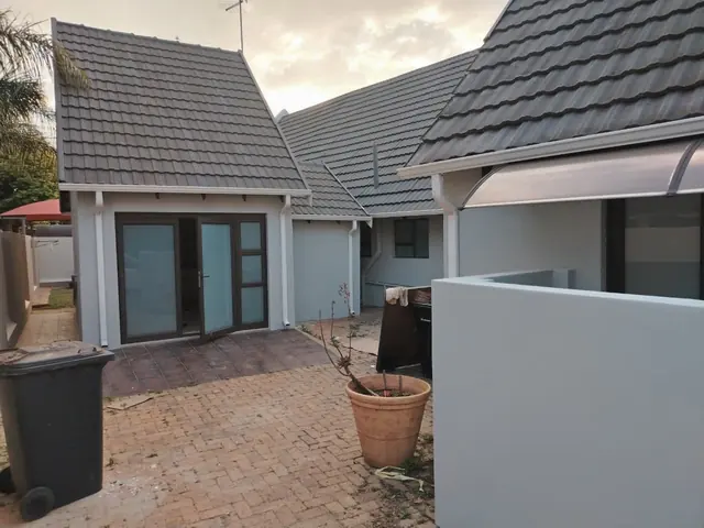 Courtyard with grey-blue painted walls, tiled roofs, French doors and a paved floor