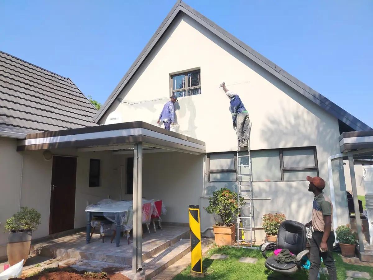 Painters on a ladder repairing cracks on the gable wall of a house