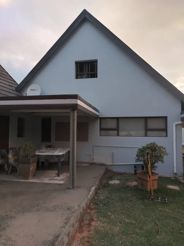 Gable-end house painted light blue-grey above a covered patio