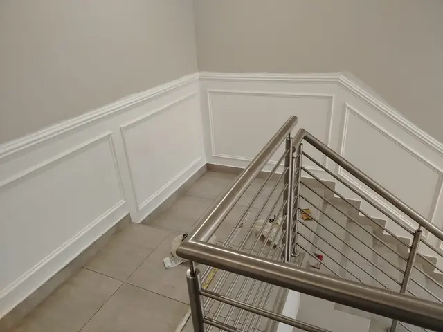 Stairwell wall with white painted panel mouldings above a tiled floor