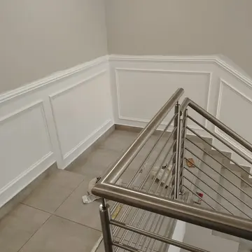 Stairwell wall with white painted panel mouldings above a tiled floor