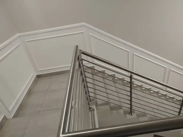 Stairwell with white painted wall panels and a stainless steel handrail