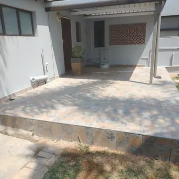 Raised tiled patio under a covered veranda beside grey painted walls
