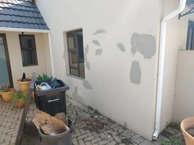 Cream exterior wall with grey filler patches ready for repainting