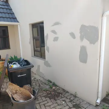 Cream exterior wall with grey filler patches ready for repainting