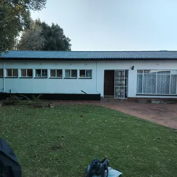 Single-storey house with white painted walls, a dark roof and a lawn in front
