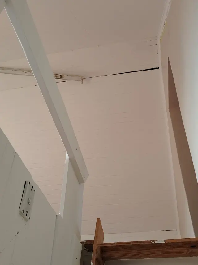 High ceiling of white painted timber planks with a white beam